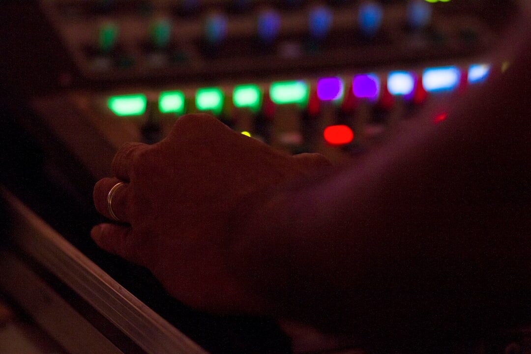Sound engineer adjusting an audio mixing console with faders and knobs
